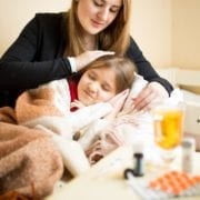 caring mother lying in bed with sick girl